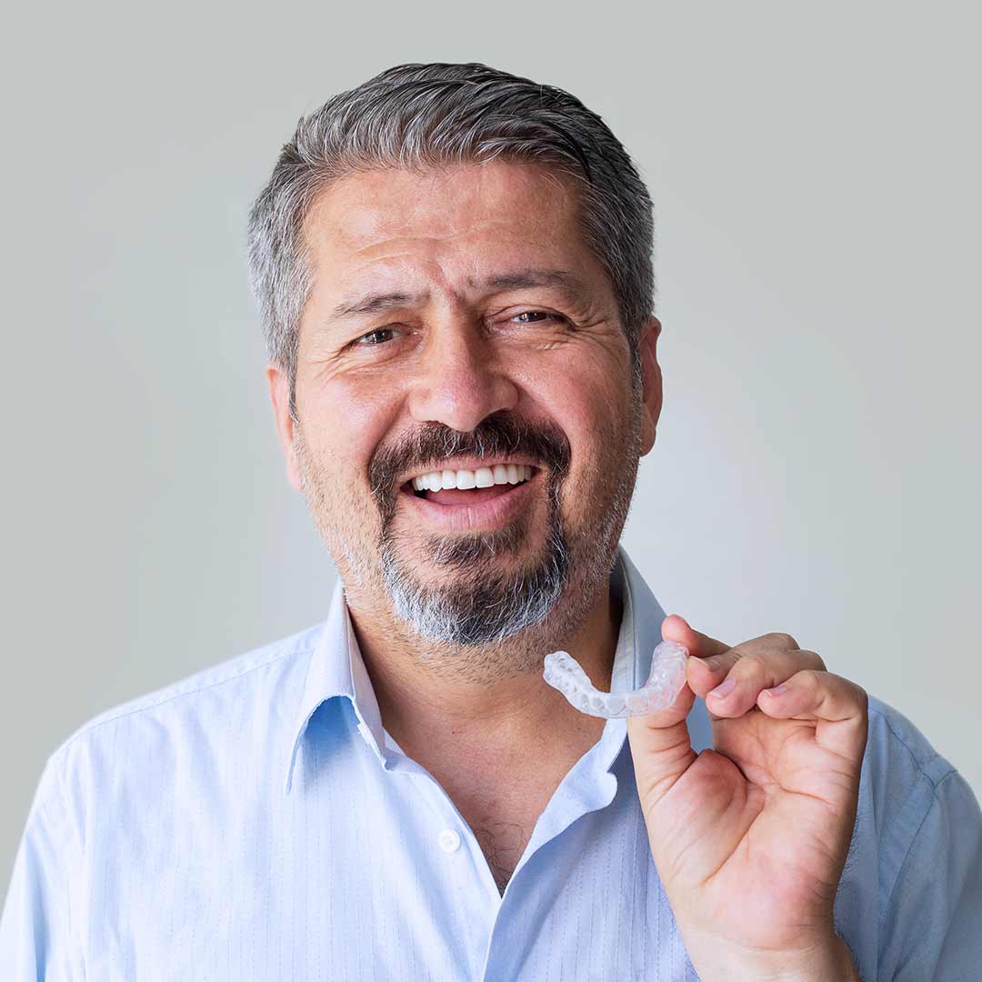 Older man holding a clear aligner - Invisalign Laguna Beach