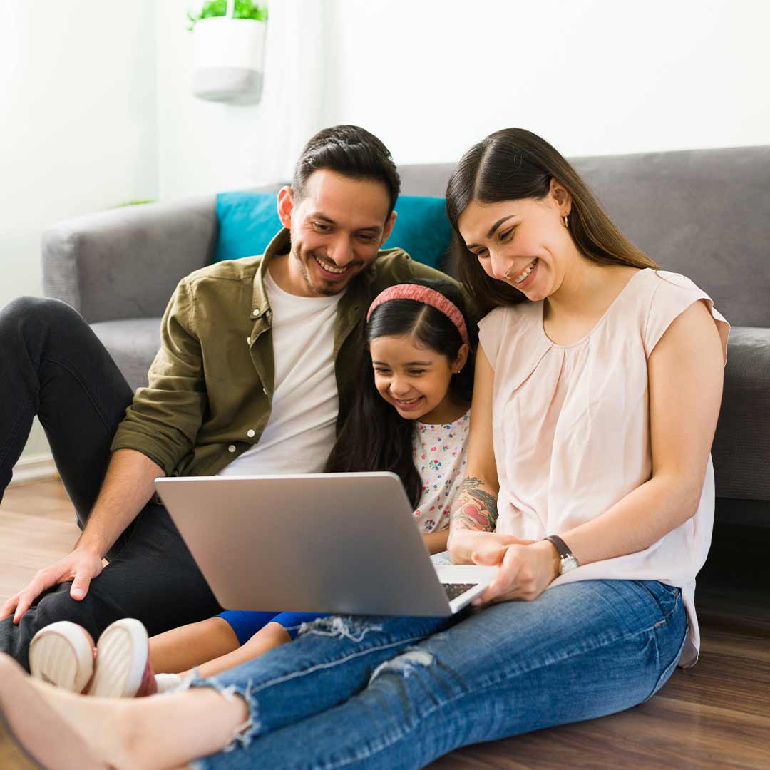 Family of three on a laptop while sitting on the floor