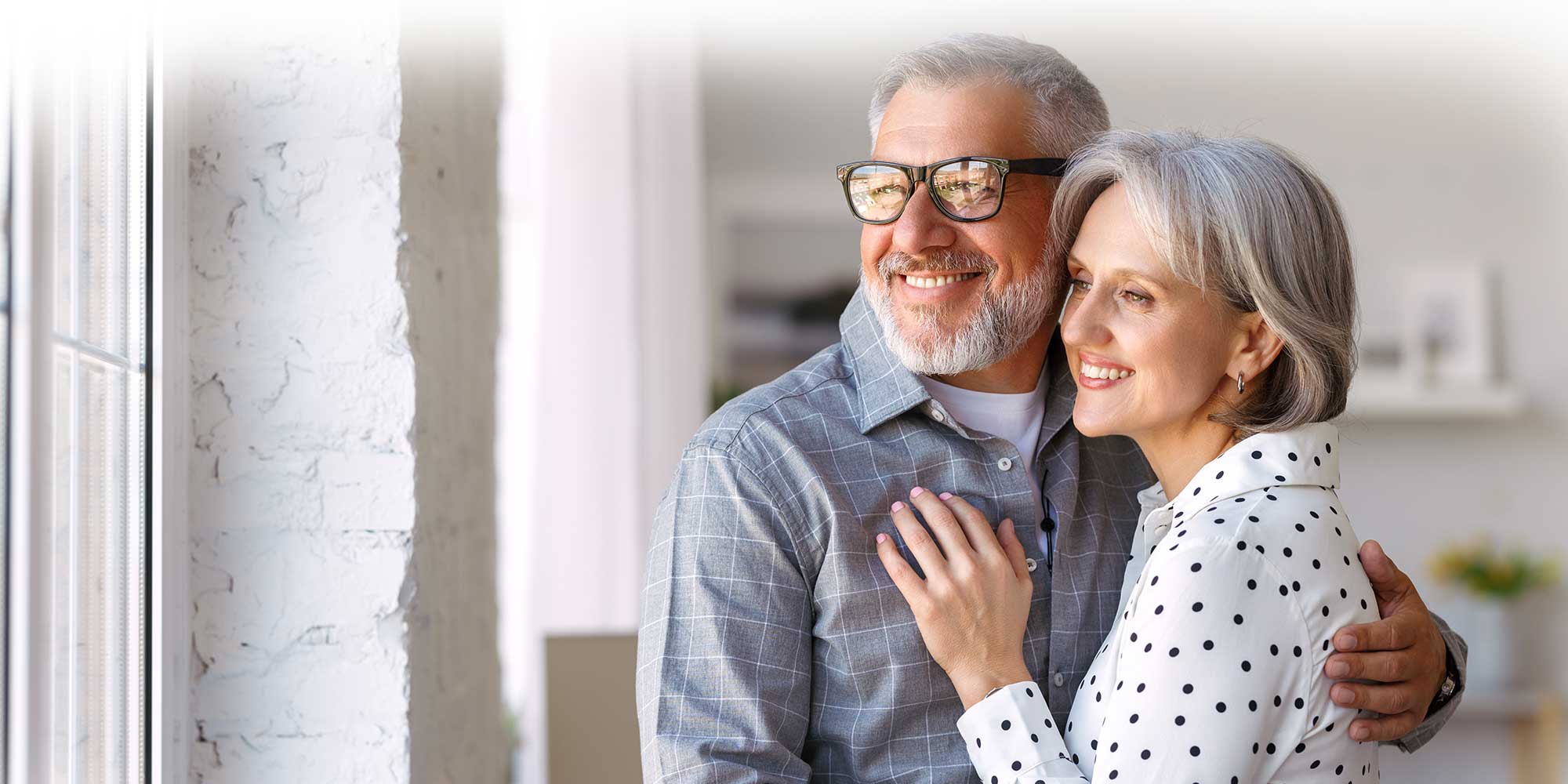 older couple smiling while looking out of a window