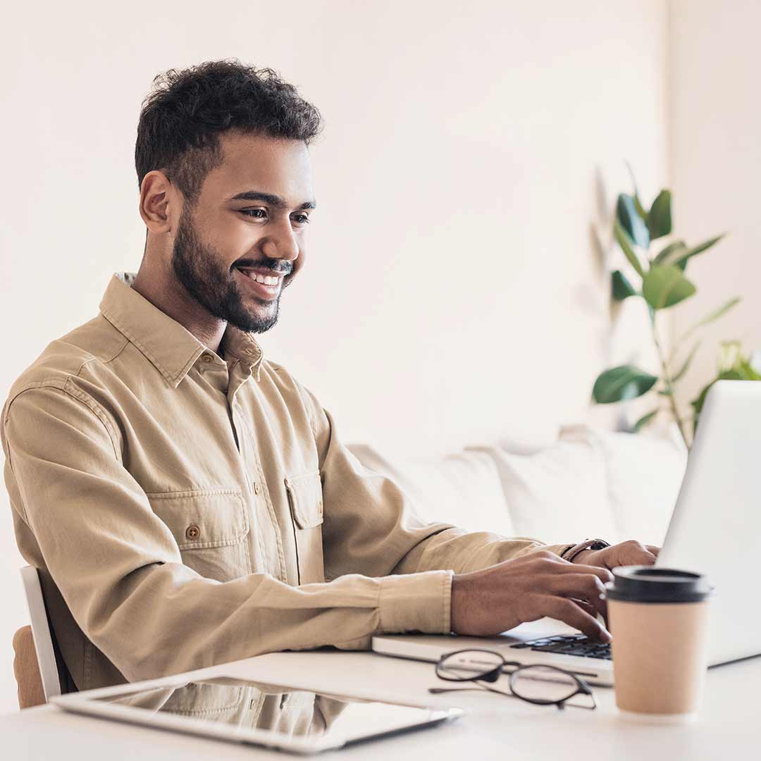 Man smiling while typing on a laptop