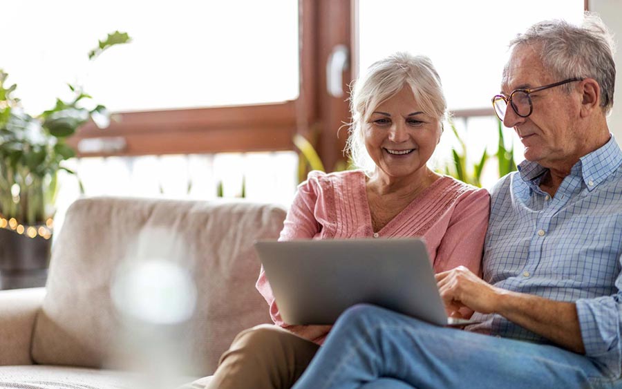 older couple looking at laptop together on a couch
